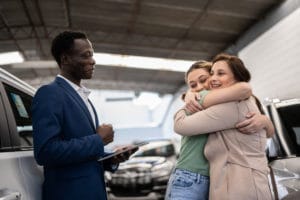 Mother and daughter embracing buying a car in a car dealership