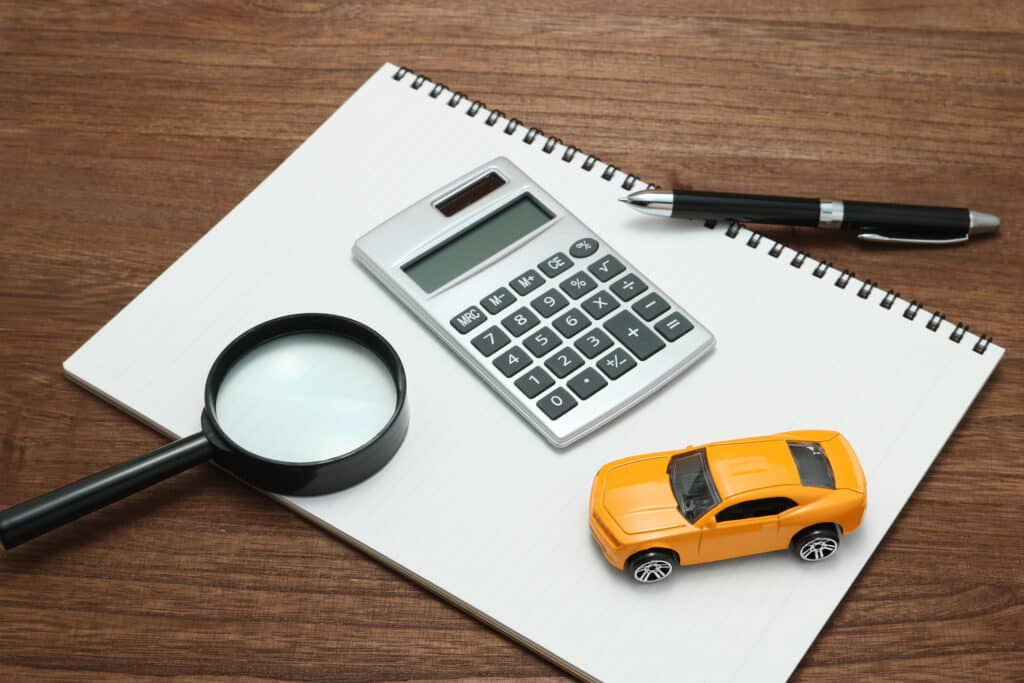 Toy car, magnifying glass, calculator, pen and notebook.