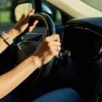 Close up view of female driver hands on steering wheel.